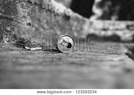 Metal can and cigarette in a park. Lying on the ground. Garbage.
