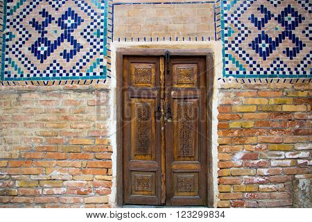 old carved wooden double doors with mosaic on the walls the Central Asian style Registan square Samarkand Uzbekistan