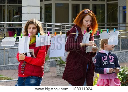 GOMEL BELARUS - SEPTEMBER 12 2015: Unidentified girl are looking the photos in the course of art-action "FotoDrying" outdoors during the City Day celebrations Gomel Belarus