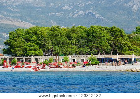 BUDVA MONTENEGRO - SEPTEMBER 19 2015: Unidentified people are relaxing on the beach of the island Sveti Nikola near the popular resort of Budva Montenegro