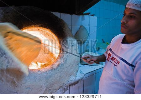 Manama, Bahrain - January 7 2007: A baker kooks the arabian bread in the old market.