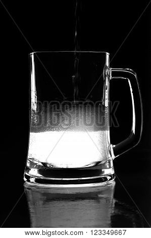 black and white photo of beer with reflection in glass with foam and bubbles
