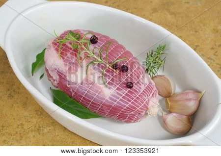 raw ham with rosemary and laurel in dish