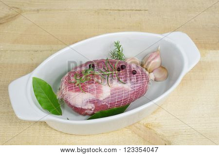 raw ham with rosemary and laurel in dish