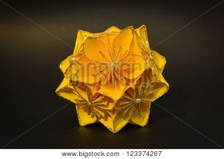 Yellow origami flower ball on the black background