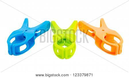 Closeup of three plastic spring clamps (Blue, Green, Orange) isolated over white background.