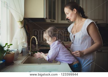 Daughter with her mother to wash their hands in the kitchen sink. casual lifestyle photo series in real life interiortoning