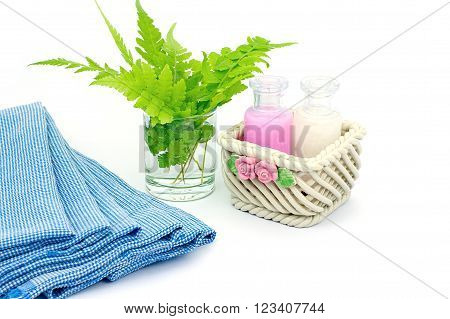 Shampoo and Shower gel put in ceramic basket on white background. Shampoo Shower gel bottles with blue cloth and green leaves in a glass of water.