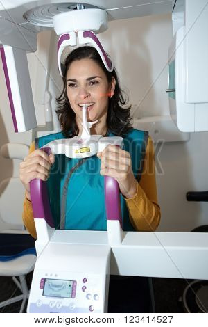 Young woman having dental panoramic x-ray in dental center by hightech digital equipment.