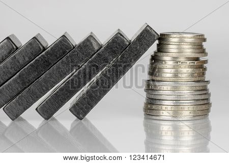 Conceptual composition of falling black domino stones as a continuous process and a pile of coins which disrupt this main process