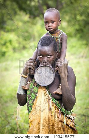 Kibish, Ethiopia, Africa - Nov 9: Tribal woman with lip plate and child on her shoulders poses for her portrait on Nov 9 2015 in Kibisch, Ethiopia.