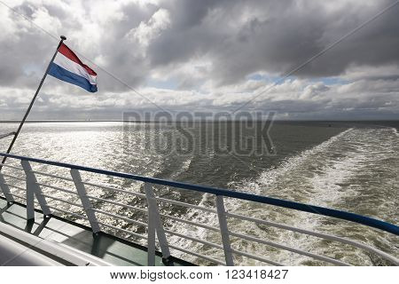 Wadden Sea with Dutch flag and wake as seen from the ferry