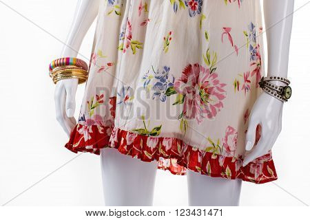 Bracelet and watch on mannequin. Female mannequin with small accessories. Floral sarafan and bracelets set. New arrivals of clothing.