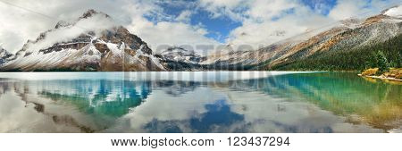 Bow Lake panorama reflection with snow capped mountain and forest in Banff National Park