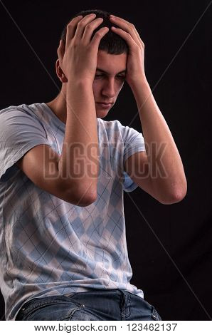 Upset Teenager With Head In Hands Wincing From Stress, Anguish Or Depression