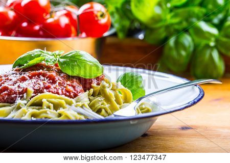 Pasta. Italian and Mediterranean cuisine. Pasta Fettuccine with tomato sauce basil leaves garlic and parmesan cheese. An old home kitchen with old kitchen utensils.
