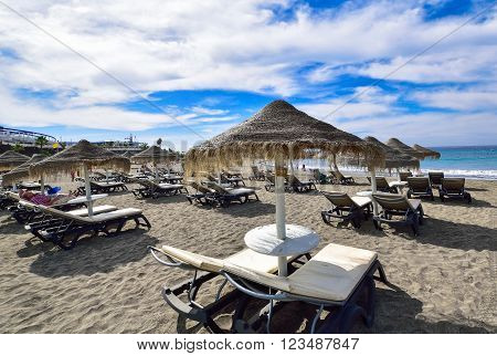 Umbrellas and chairs on Fanabe beach in summertime in Tenerife, Spain