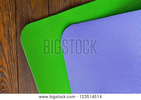 New yogamat green and purple on a wooden background. Facilities for training and yoga. Weight loss and fitness. Diagonal. The concept of love to a healthy lifestyle.