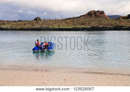 GALAPAGOS ECUADOR - APRIL 20: Unidentified men drive dinghy on April 20 2015 on Chinese Hat island in Galapagos National Park Ecuador. This park is a UNESCO World Heritage Site