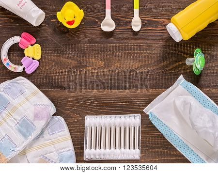 Japanese diapers wet wipes baby powder cream tither cotton buds spoons soother and duckling on wooden background. Flat lay. Text font from open sources free license of use