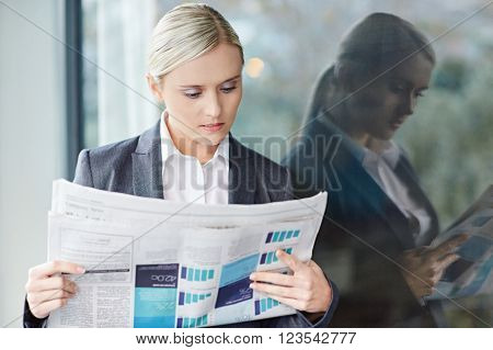 A young businesswoman reading the newpaper outside her office