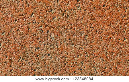 Rough painted red wall is photographed in daylight
