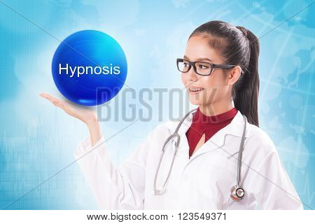 Female doctor holding blue crystal ball with hypnosis sign on medical background.