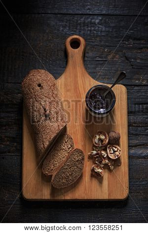 The top view of fruity jam and spoon and knife on black wooden table and bread