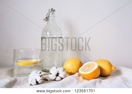 Tasty cool beverage with  fresh lemons on white cotton fabric