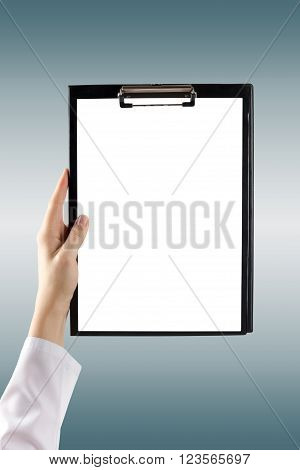 Female doctor's hand holding medical clipboard with blank sheet of paper on blie blurred background. Concept Healthcare And Medicine. Copy space.