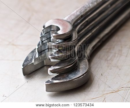 Pyramid of 5 silver wrenches on the scratched background