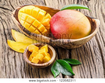Mango fruit and mango cubes on the wooden table.