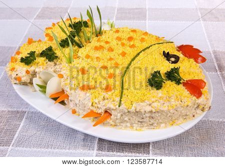 Fish salad in the shape of a fish, with boiled eggs and greenery on tablecloth