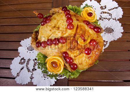 Baked chicken decorated with berries, greens and lemons, on the table