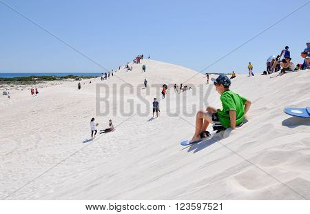LANCELIN,WA,AUSTRALIA-SEPTEMBER 28,2015: People sand surfing and sledding down the white sand dunes in Lancelin, Western Australia.