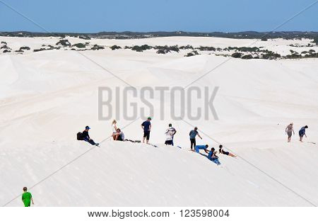 LANCELIN,WA,AUSTRALIA-SEPTEMBER 28,2015: Families sand surfing and sledding the white sand dunes in Lancelin, Western Australia.