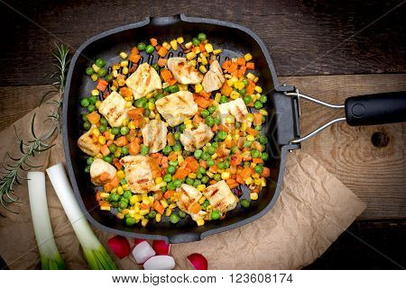Grilled - roasted chicken meat (chicken breast) and vegetables in pan on rustic wooden background