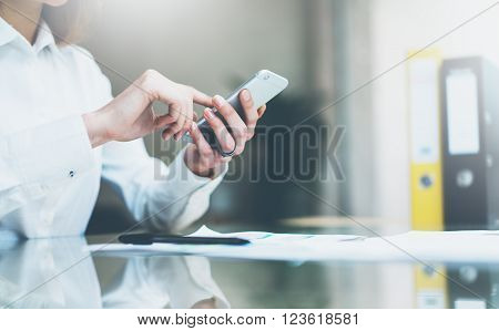 New business startup. Photo young businesswoman working new startup project modern office.Contemporary smartphone holding female hands and touching screen.Analyze statistics, plans table