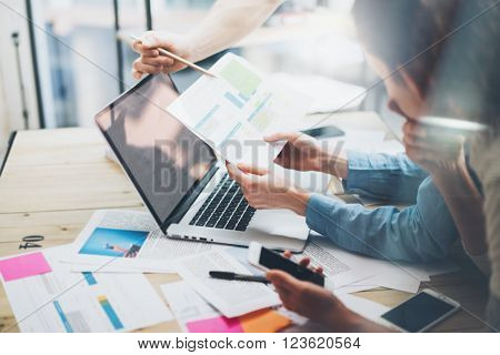 Team account manager project work.Photo business managers working with new startup in modern loft.Analyze reports, plans. Notebook on wood table, papers, documents, statistics.