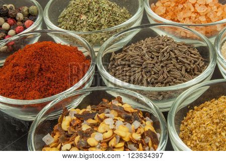Various kinds of spices in glass bowls on a slate background. Preparation for cooking spicy food. Spices for master cook. The spice trade. Sale of spices in the kitchen.