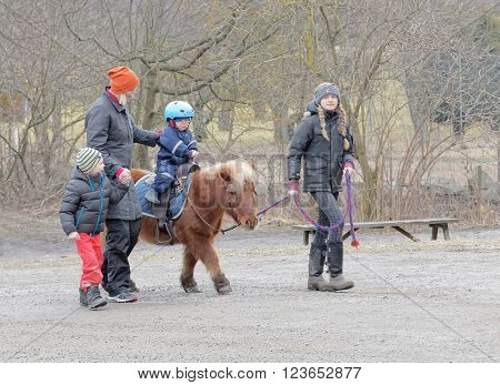 STOCKHOLM SWEDEN - MAR 20 2016: Small pony and a small child riding a groom leading the horse at Oeverjarva Gard Mars 20 2016 Stockholm Sweden