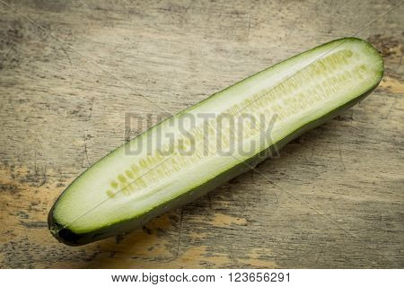 Cucumber sliced lengthwise with seeds on grungy wooden table