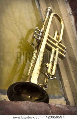 Old worn trumpet stands alone against a grungy wall