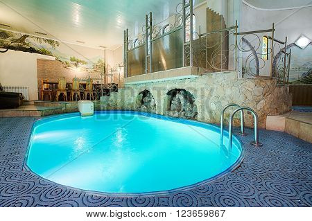 Blue swimming pool in modern spa interior. Resort and wellness. Blue clear water indoor pool in spa center. Healthcare and rest, relaxation concept.
