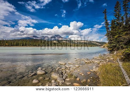 Evergreen forests and snow-capped Rocky Mountains of Canada. Beneaped Medicine Lake in the fall