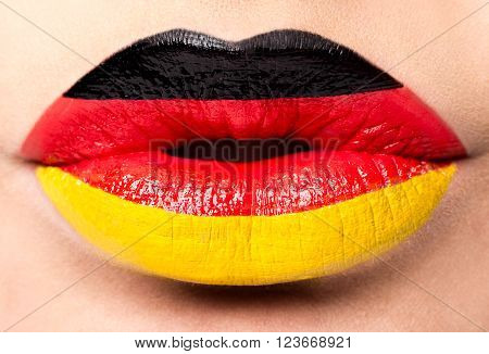 Female lips close up with a picture of the flag of Germany. black, red, yellow