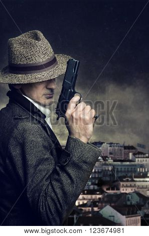 A gangster with hat holding a handgun with a city in the background