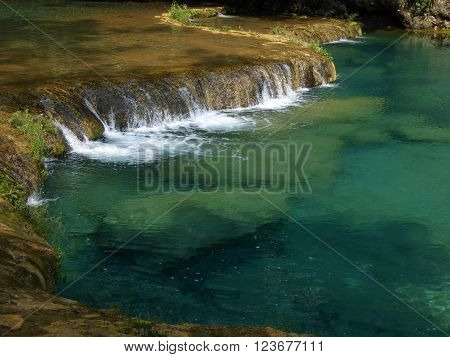 Small cascades off a natural limestone dam in the clear turquoise pools of Semuc Champey Guatemala.