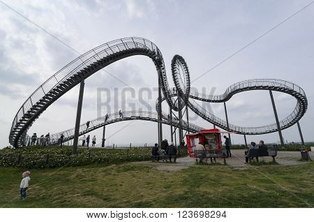 Duisburg, Germany - May 18, 2015: Tiger and Turtle Roller coaster magic Mountain with people visiting it. This sculpture is an art installation and landmark in Angerpark Duisburg 
Germany.