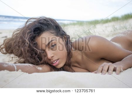 Pretty and nude girl is sleeping on beach in sand